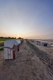 White beach chair and beach with beach promenade in the backlight of the sunset in the district of