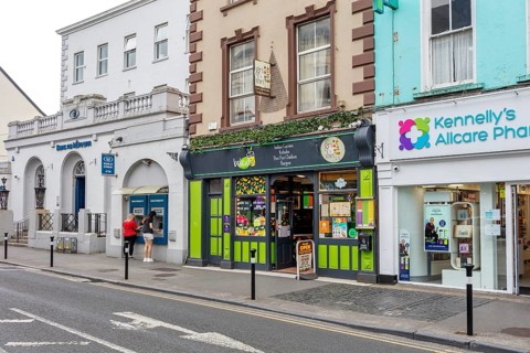 Shops and pharmacy along a busy street with mixed historic and modern facades, Tralee