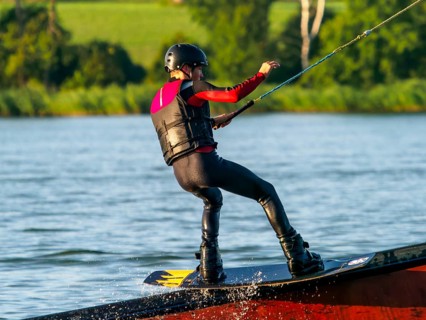 Young man with wakeboard on obstacle, water sports, water skiing in wakepark
