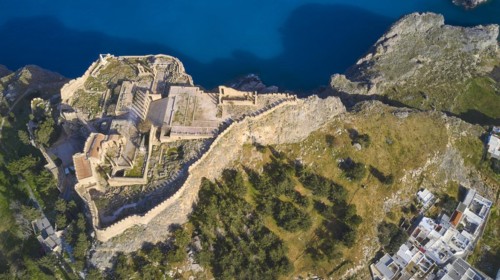 Drone shot, Acropolis of Lindos, late afternoon light, aerial view of a ruined fortress on a cliff