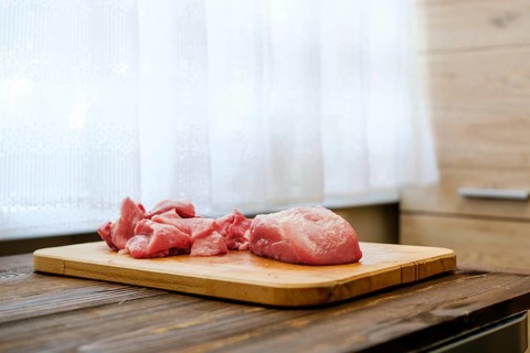 Raw pork shoulder on wooden cutting board in the kitchen