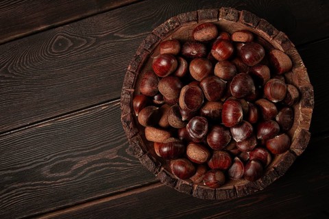 Fresh chestnuts, in a wooden bowl, top view, no people