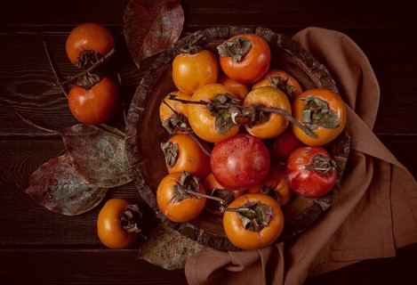 Fresh persimmon, in a wooden plate, top view, no people