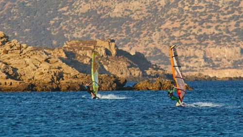 Two windsurfers in rough sea off rocky coast, windsurfer, Meltemi windsurfing spot, Devils Bay,