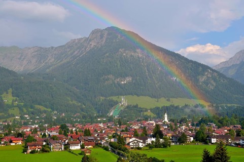 View over Oberstdorf with rainbow, behind it the Schattenberg with Schattenbergschanze, Oberallgäu,