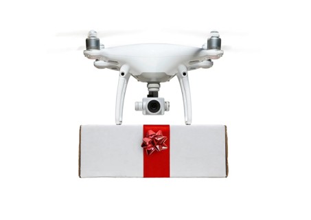 Unmanned UAV drone quadcopter delivering A package with a red ribbon and bow isolated on a white