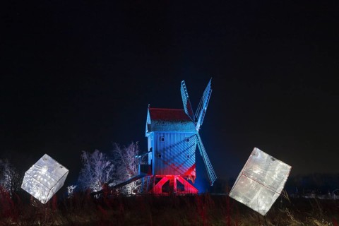 An illuminated windmill with abstract cubes in the foreground at night, world of lights,