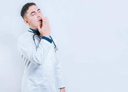Young sleepy doctor yawning on isolated background. Tired of working doctor concept. Tired and