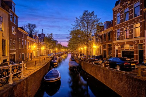 Typical Netherlands view, canal with boats and houses illuminated in the evening. Haarlem,