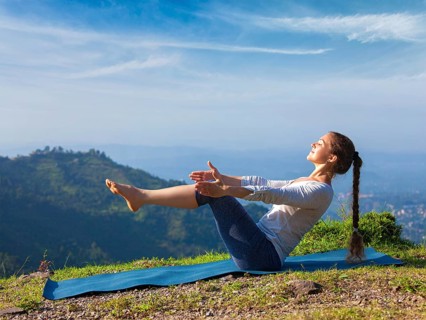 Yoga outdoors, young sporty fit woman doing Ashtanga Vinyasa Yoga asana Navasana, boat pose easy