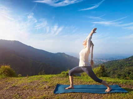Yoga outdoors, sporty fit woman doing yoga asana Virabhadrasana 1, Warrior pose posture outdoors in
