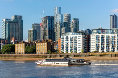 Uber boat water bus service passing Canary Wharf, Isle of Dogs, London, England, UK