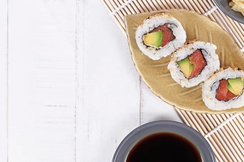 Sushi inside out rolls with salmon, avocado and sesame on small leaf shaped plateSushi inside out
