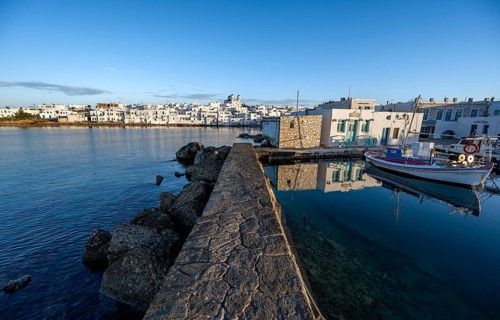 Harbour wall, local view of Naoussa town and blue sea, harbour with fishing boats and reflection,