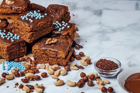 Brownies filled with jam and ingredients for decoration, chocolate icing, nut mix, chocolate