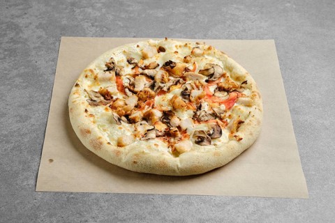 Pizza with chicken breast and champignon mushrooms on parchment paper