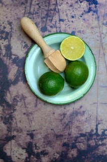 Limes with citrus squeezer on plate