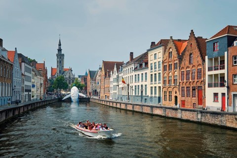 BRUGES, BELGIUM, MAY 29, 2018: Tourist boat in canal between old houses with The Bruges Whale
