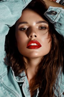 Beautiful sexy girl with bright makeup, red lips, wet hair in a denim jacket. Beauty face. Photo