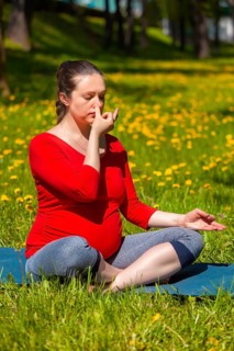 Pregnancy yoga exercise, pregnant woman doing pranayama breath exercise in Sukhasana easy yoga pose