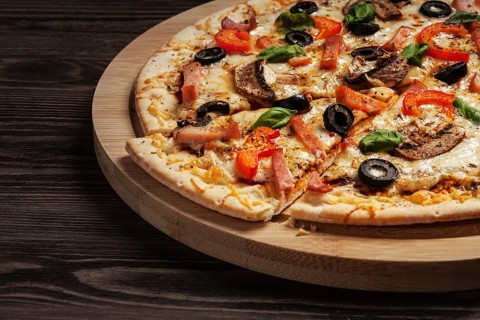 Ham pizza with (capsicum), mushrooms, olives and basil leaves on wooden board on old table close up
