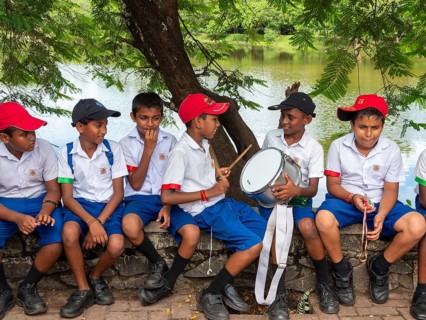 School children school uniform sitting on wall and drumming, Sri Lanka, Asia