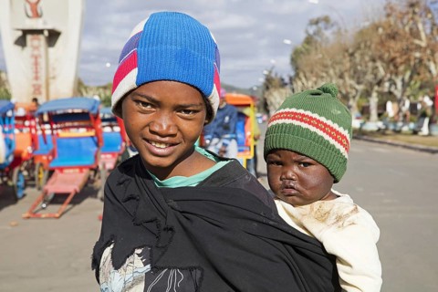 Young Malagasy girl carrying child on her back in the city Antsirabe, Vakinankaratra, Madagascar,