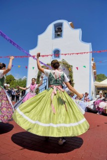 Women in traditional dress dance in front of the Ermita de San Vicent chapel, annual fiesta in