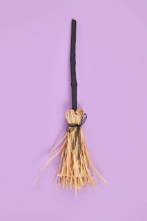 Witch broom with black twig and straw bristles on violet background