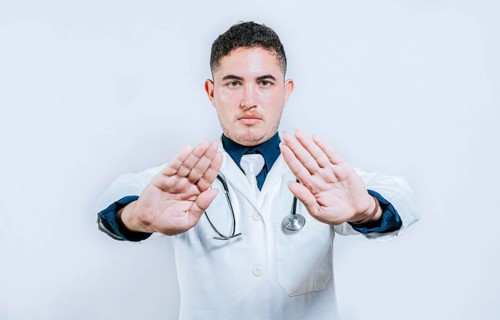 Doctor making a stop gesture with palms on white background. Latin doctor making a stop gesture