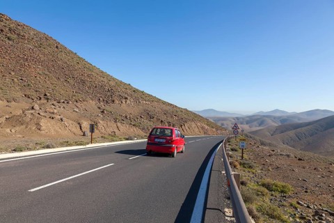 Red small car driving on the road FV-605, Fuerteventura, Canary Island, Canary Islands, Spain,