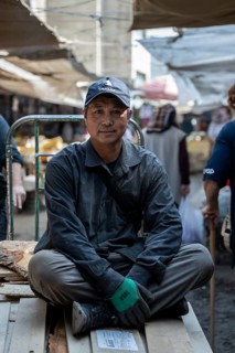 Worker sitting on planks, Osh Bazaar, Bishkek, Kyrgyzstan, Asia