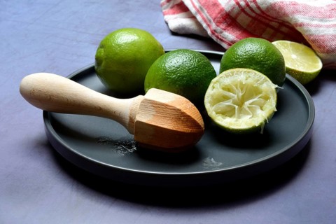 Limes with citrus squeezer on plate