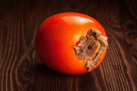 Fresh ripe persimmon on a wooden background