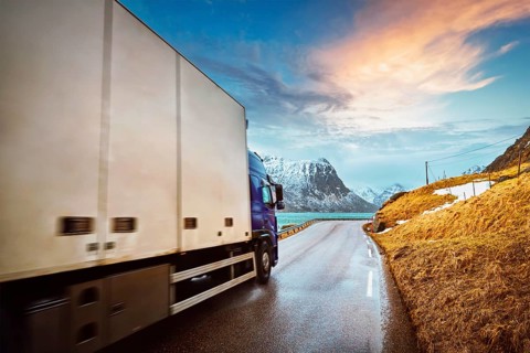 Truck on road in Norwegian fjord on sunset. Lofoten islands, Norway. Motion blur