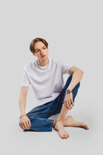 Young barefoot man sits on the floor in studio in t-shirt and jean