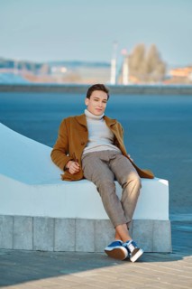 Spring, autumn outfit. Street fashion. Young man in checkered trousers, sweater and wool coat