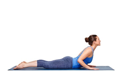 Beautiful sporty fit yogini woman practices yoga asana bhujangasana, cobra pose beginner variation