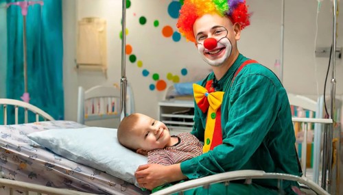 A clown, a clinic clown, in mask, red nose and costume with a sick child in the clinic, AI
