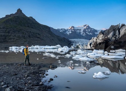 Hikers at a lake, reflection in the Svínafellslon glacier lagoon with ice floes, Svínasfellsjökull
