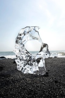 Ice, piece of ice with hole on black sand beach, on black lava beach Diamond Beach, Southeast