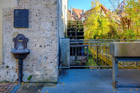 Commemorative plaque Eduard Mörike, drinking water basin and historic mill wheel at the