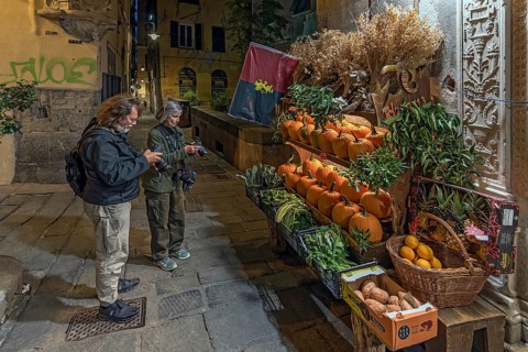 Tourists photographing a fruit shop in the evening in the historic centre, Genoa, Italy, Europe
