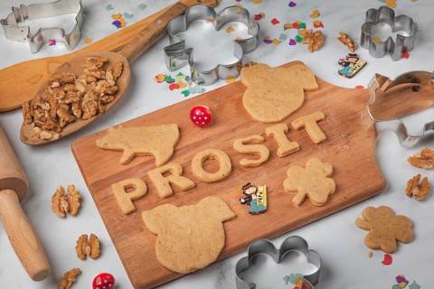 Cheers lettering made from biscuit dough and cut-out biscuits on a wooden board, baking
