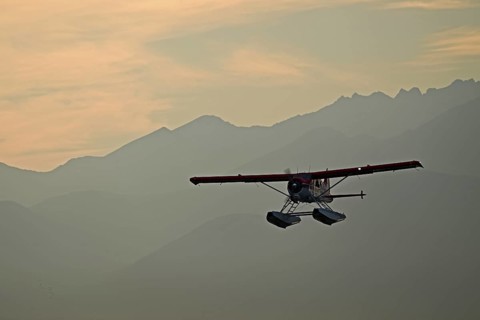 A Beaver De Havilland bush plane with floats against the backdrop of the Chugach Mountains on
