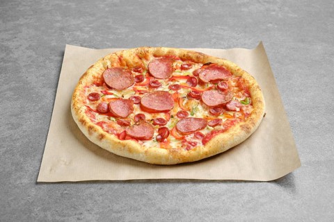 Top view of pizza with sausage and colorful bell pepper on parchment