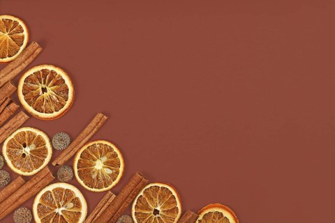 Seasonal flat lay with natural dried orange slices, cinnamon sticks and acorn hats in corner of