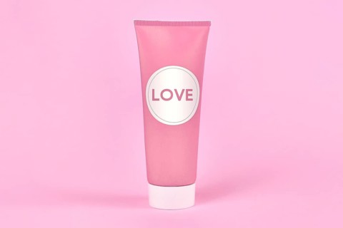 Love concept with cream tube with made up label saying LOVE on pink background