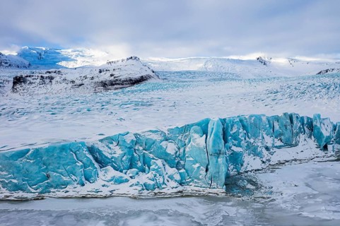 Snow-covered icebergs in the Fjallsarlon glacier lagoon, with the Öraefajökull glacier behind,