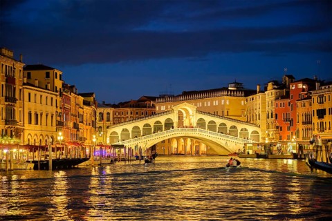Famous Venetian tourist landmark Rialto bridge (Ponte di Rialto) over Grand Canal illuminated at
